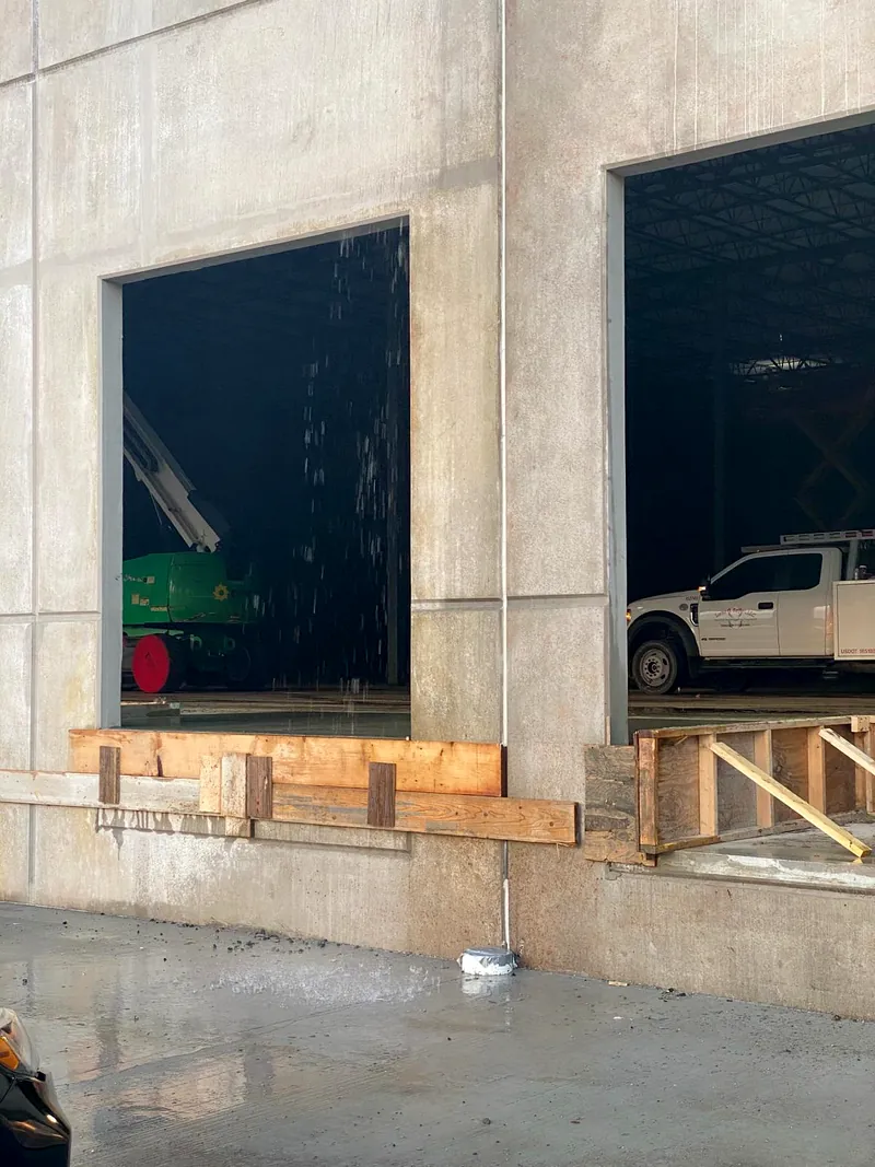 Two dock openings in bare concrete walls shored with timber, a lift and a truck visible inside the building