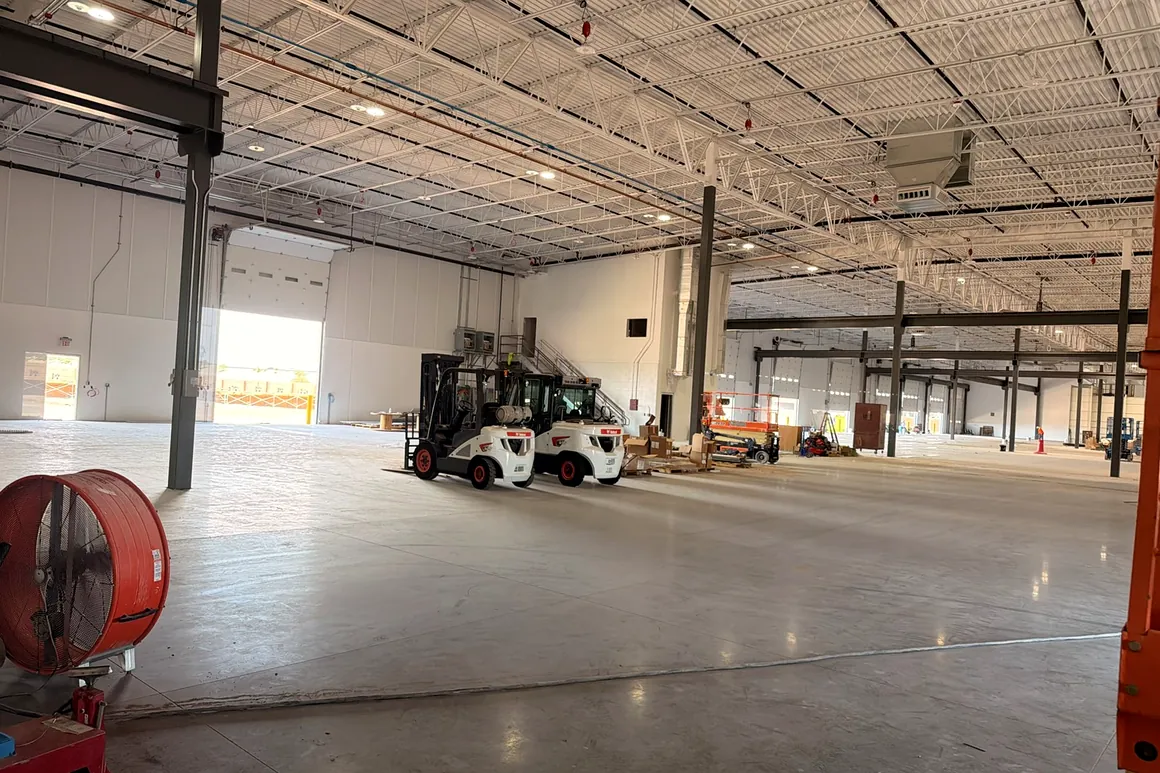 Distribution warehouse interior with white painted walls and overhead structure above a sealed concrete floor